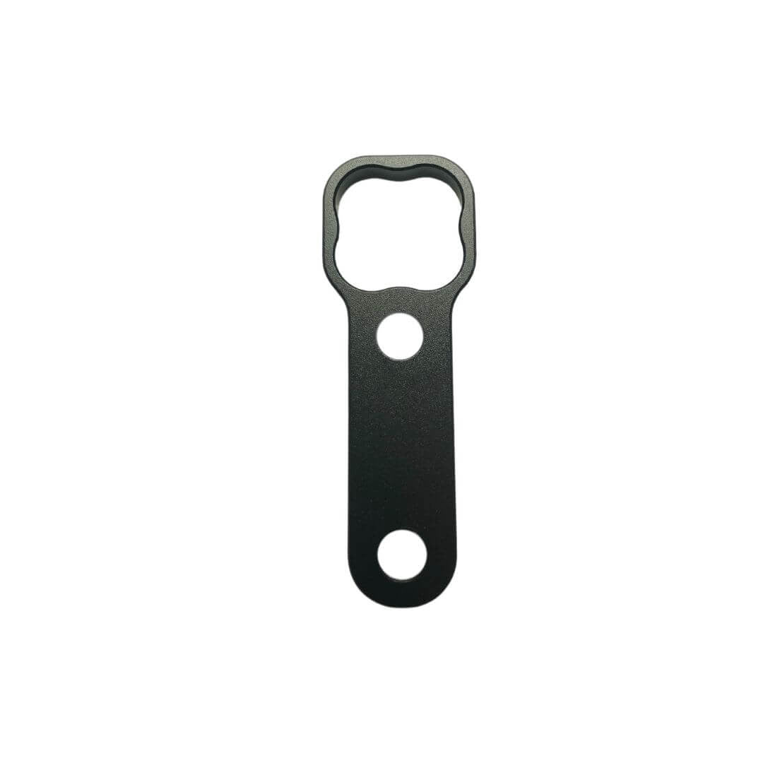 Black anodized billet aluminum wrench for Tuff-Kase II showing custom clover-shaped drive head, central locating hole, and lower grip hole on a white background