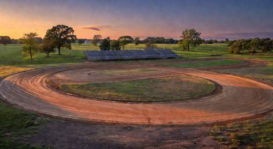 Dusk landscape of a Midwest dirt kart track with grandstands and fields.