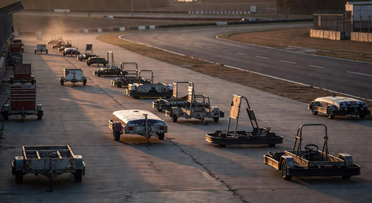 Empty karting pit lane at dusk with trailers and stands.