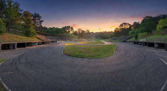 Paved sprint kart track landscape at dusk with wooded surroundings