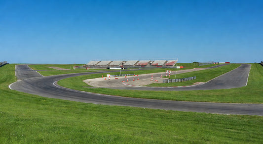 Paved sprint kart track landscape with open pits under blue skies.
