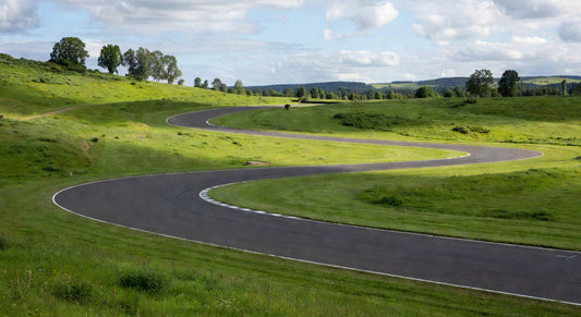 Paved sprint kart track winding through green hills under clear skies