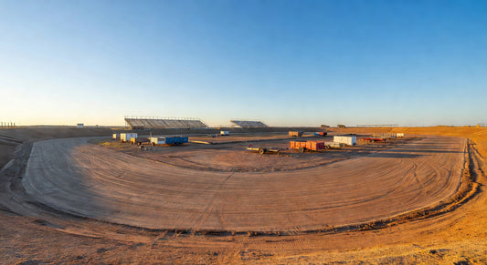 Expansive dirt oval kart track landscape on a sunny day.