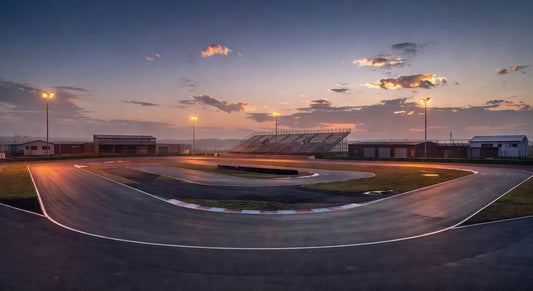 Dusk landscape of a sprint kart track with curving pavement and distant pits.
