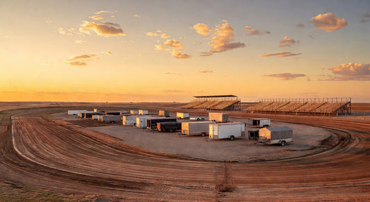 Golden hour view of a dirt oval karting track and pits
