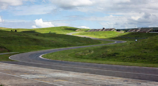 Paved sprint kart track landscape with curving turns and distant grandstands