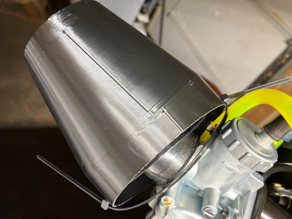 Black 3D printed rain hood installed on LO206 carburetor secured with zip tie in workshop