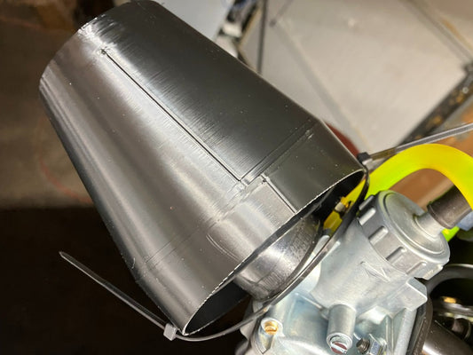 Black 3D printed rain hood installed on LO206 carburetor secured with zip tie in workshop