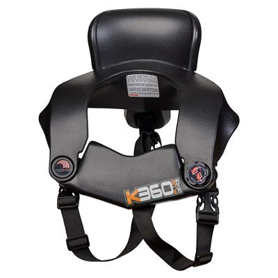 Front view of black K360 Plus Device Kid neck brace showing headrest pad, curved shoulder wings, orange accented adjusters, front logo and harness straps on a white background