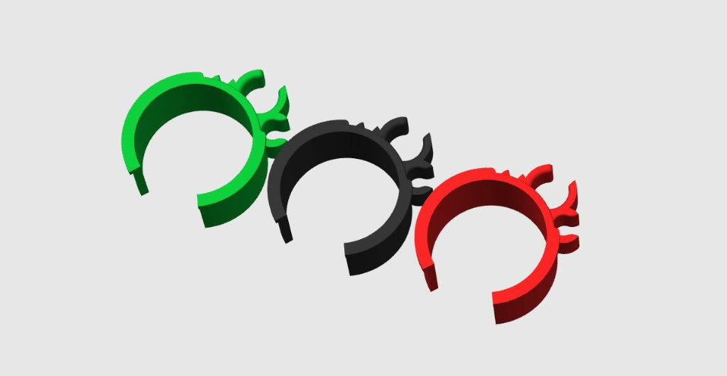 Green, black and red 3D printed cable management clips lined up to show profile and grip tabs on a gray background