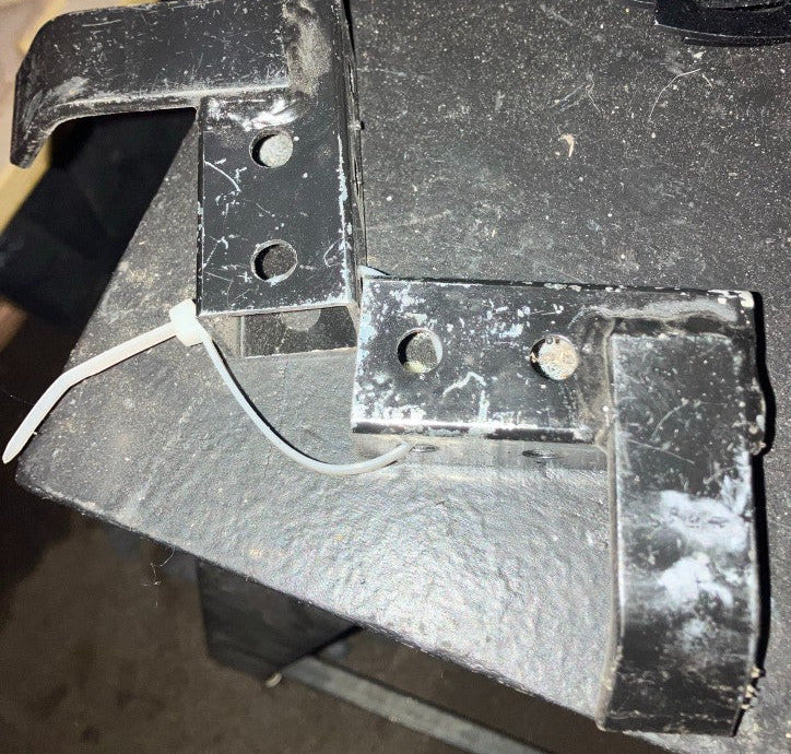 Bare metal steel kart stand pickup bracket highlighting raised L-hook for bumper and side flange on a workbench