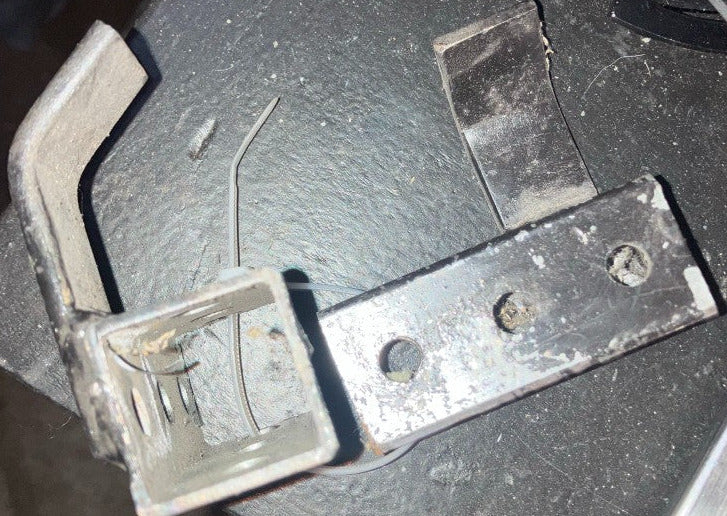 End view of bare metal kart stand pickup bracket showing square tube receiver and hook detail on a workbench