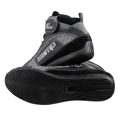 Close-up of the ultra-grip rubber sole on black Zamp ZK-20 kart shoe with aggressive tread pattern, stacked view showing heel construction on a white background